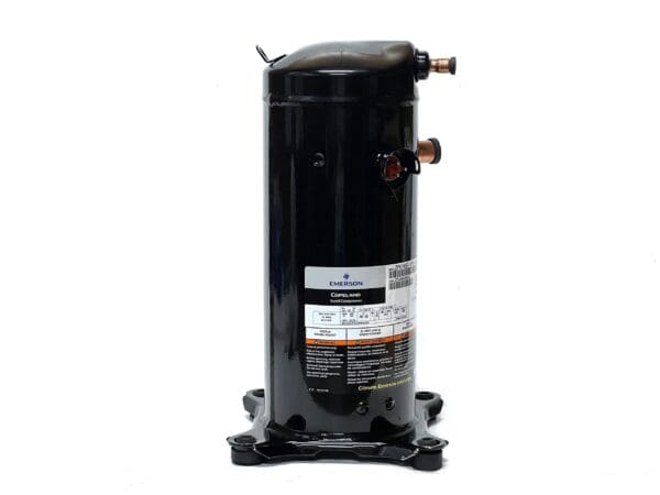 A black compressor is sitting on top of the ground.